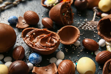 Easter eggs with chocolate paste and candies on dark background, closeup