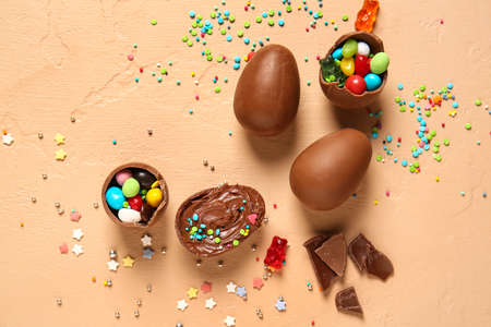Composition with chocolate Easter eggs, candies and sprinkles on beige background