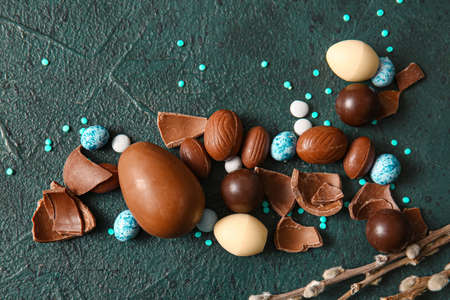 composition with broken chocolate Easter eggs and candies on dark background
