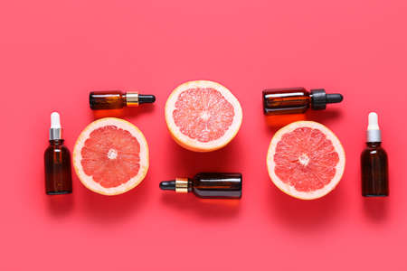Composition with bottles of essential oil and juicy grapefruits on color backgroundの写真素材