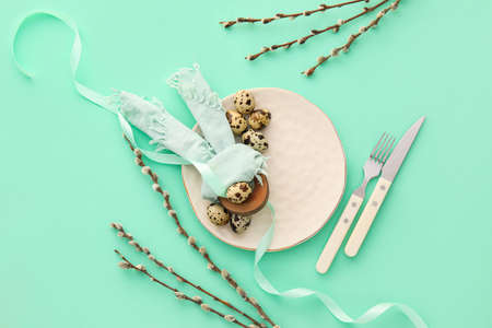Beautiful table setting for Easter celebration and pussy willow branches on color backgroundの写真素材