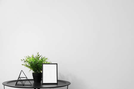 Table with frame, houseplant and decor near light wallの写真素材