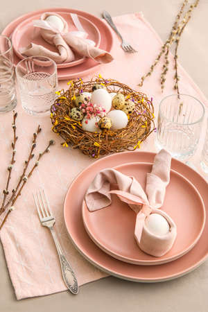 Beautiful table setting for Easter celebration and pussy willow branches on gray background