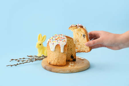 Woman holding piece of delicious Easter cake on blue background
