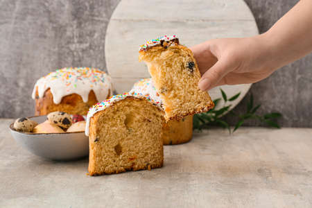 Woman holding piece of delicious Easter cake on gray background