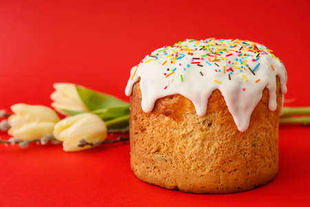 Delicious Easter cake and tulip flowers on red background