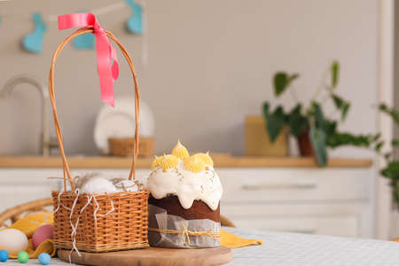 Tasty Easter cakes, basket and eggs on table in kitchen