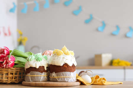 Tasty Easter cakes, eggs and tulips on table in kitchenの写真素材