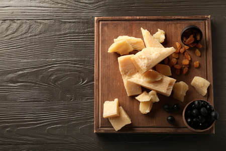 Board with pieces of tasty Parmesan cheese on brown wooden backgroundの写真素材