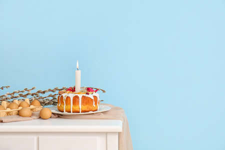 Easter cake, holder with eggs and pussy willow branches on table near color wallの写真素材