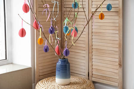 Vase with tree branches and Easter decor in the room