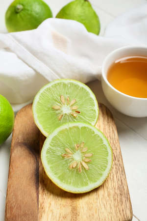 Board with slices of ripe bergamot fruit on light wooden background, closeup