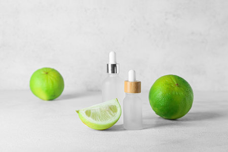 Bottles of bergamot essential oil and ripe fruits on light backgroundの写真素材