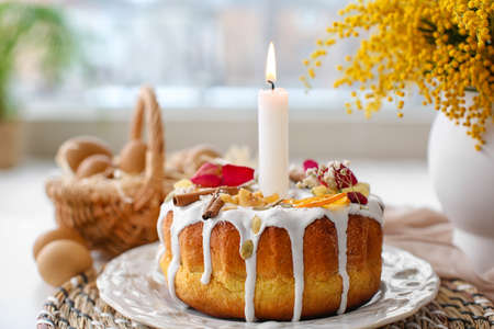 Easter cake with burning candle on table