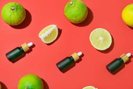 Composition with bottles of essential oil and ripe bergamot fruits on red backgroundの写真素材