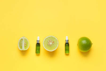 Bottles of essential oil and bergamot fruits on yellow backgroundの写真素材