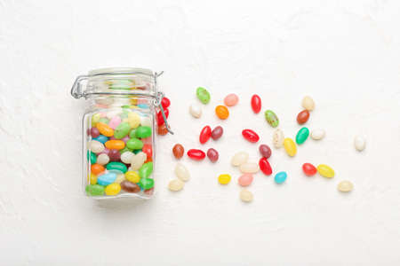 Glass jar with different jelly beans on light backgroundの写真素材