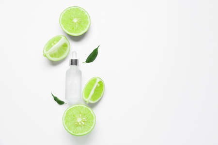 Composition with bottle of essential oil and cut bergamot fruits on white background