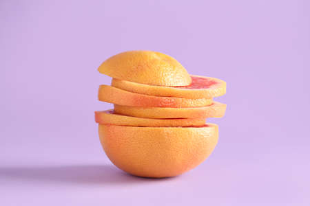 Slices of tasty ripe grapefruit on purple backgroundの写真素材