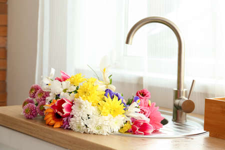 Bouquet of beautiful flowers in sink near windowの写真素材