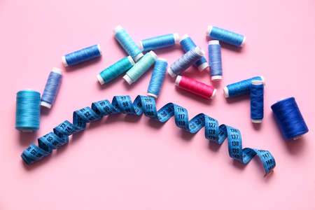 Thread spools and measuring tape on pink backgroundの写真素材
