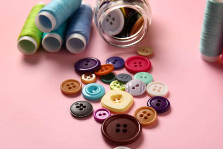 Thread spools and buttons on pink backgroundの写真素材