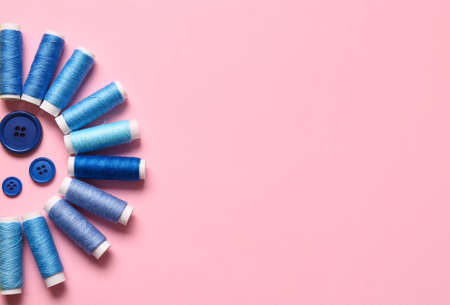 Thread spools and buttons on pink background