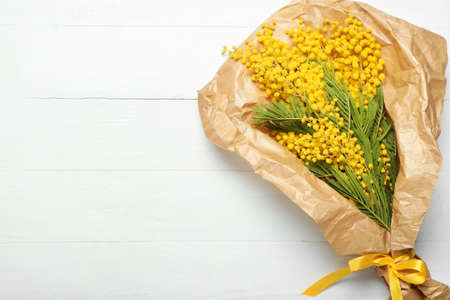 Beautiful bouquet of mimosa branches on light wooden backgroundの写真素材