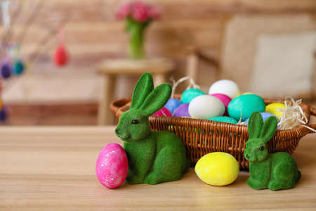 Easter rabbits and basket with eggs on tableの写真素材