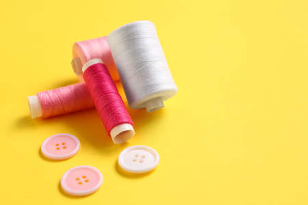 Thread spools and buttons on yellow backgroundの写真素材