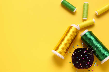Thread spools and ball pins on yellow backgroundの写真素材