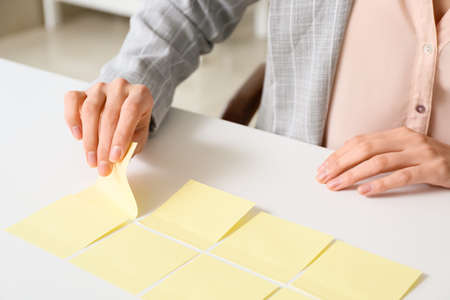 Young manager with sticky note papers at her workplace, closeup