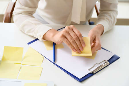 Young manager with sticky note papers working in office, closeup