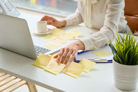 Young manager with sticky note papers and laptop working in officeの写真素材