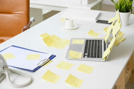 Laptop, stationery and sticky note papers on office tableの写真素材