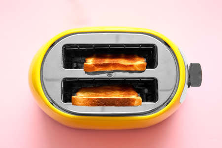 Modern toaster with bread slices on pink background