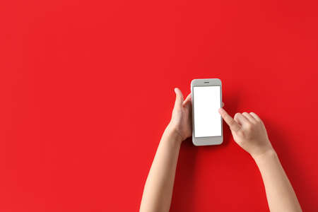 Child using modern mobile phone on red backgroundの写真素材