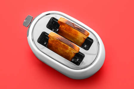 Modern toaster with bread slices on red background