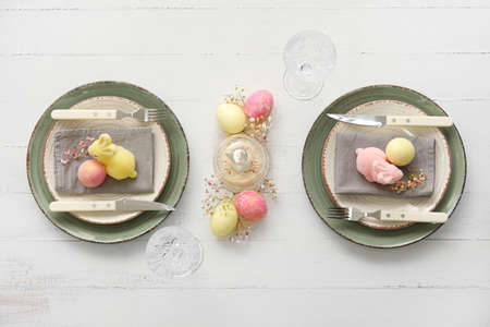 Stylish table setting for Easter celebration on white wooden background