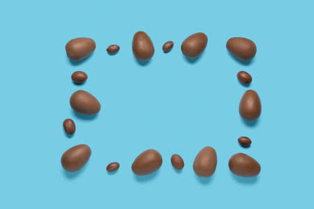 Frame made of delicious chocolate eggs on blue background