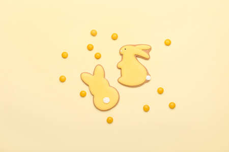 Tasty Easter cookies in shape on bunny and candies on beige background