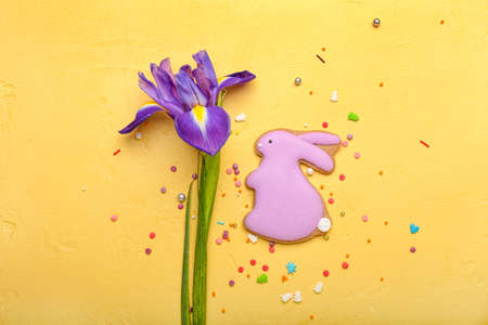 Tasty Easter cookie in shape on bunny and iris flower on yellow background