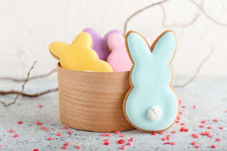 Bowl with tasty Easter cookies in shape on bunny on light background