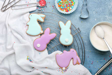 Grid with tasty Easter cookies in shape on bunny on blue background