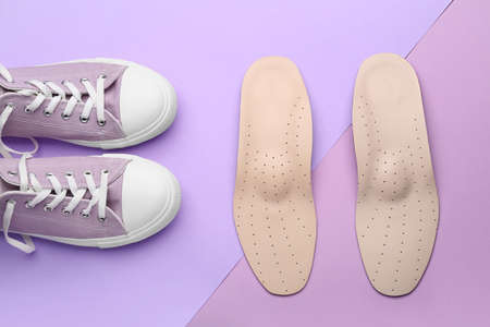 Pair of orthopedic insoles and shoes on lilac backgroundの写真素材