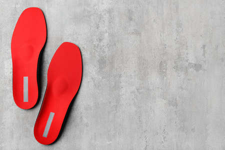 Pair of red orthopedic insoles on grunge background
