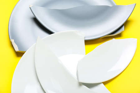 Broken ceramic plates on yellow background, closeupの写真素材