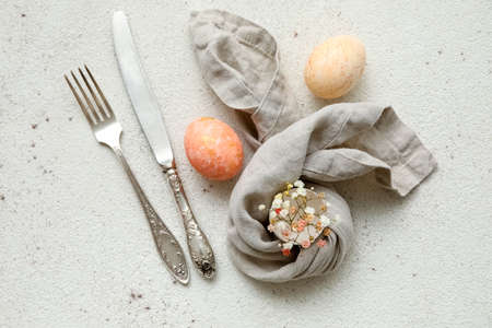 Stylish table setting for Easter celebration and gypsophila flowers on light background