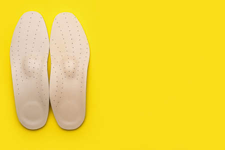 Pair of orthopedic insoles on yellow backgroundの写真素材