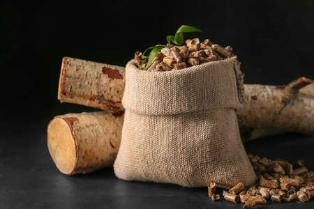 Bag with pellets and firewood on dark backgroundの写真素材